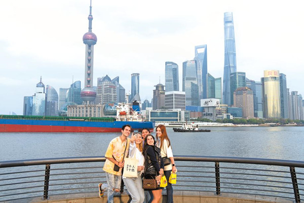 Visitors to the Bund in Shanghai in April pose for a photograph, with the Pudong financial district in the background.