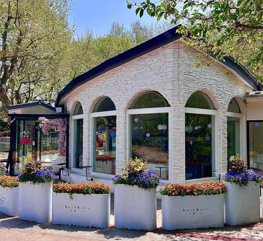 Flower beds encircle the white glasshouse.jpg