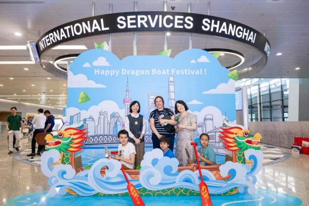 International travelers pose for a photo at the International Services Shanghai one-stop service station decorated with Dragon Boat Festival motifs..png