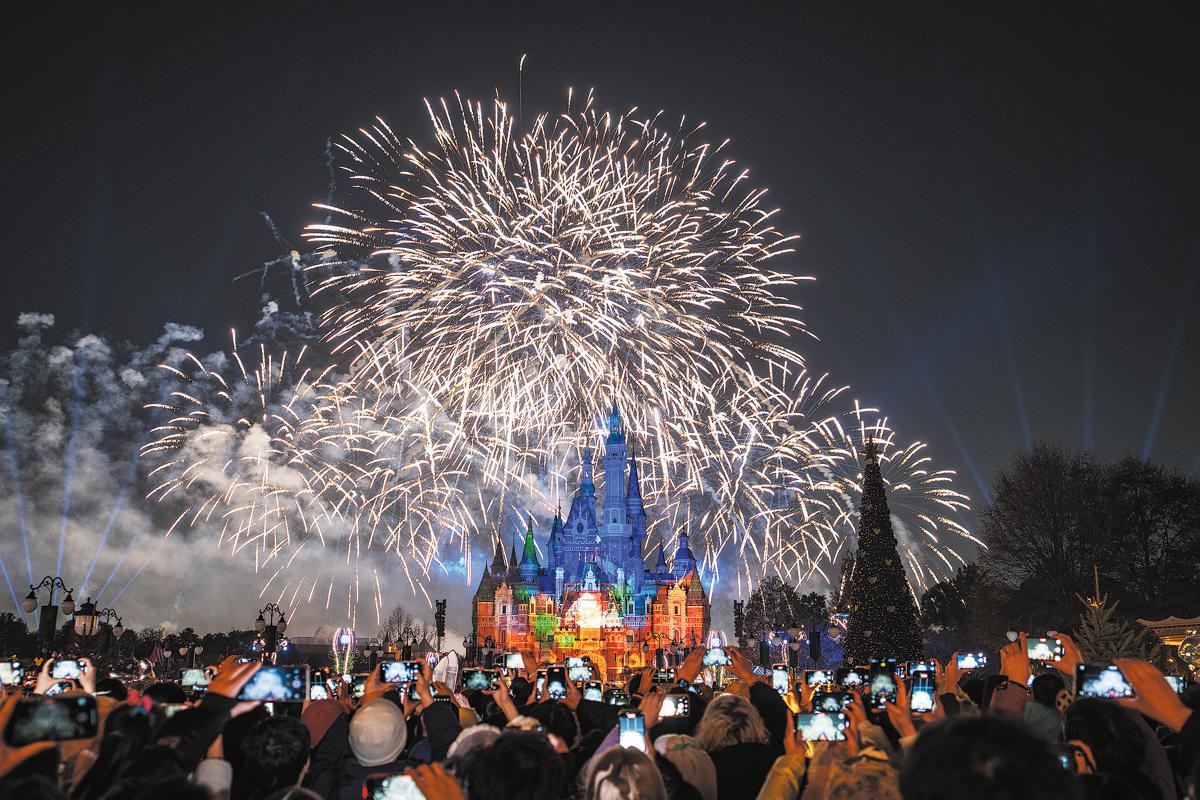 Visitors take photos of a fireworks show at Shanghai Disneyland on New Year