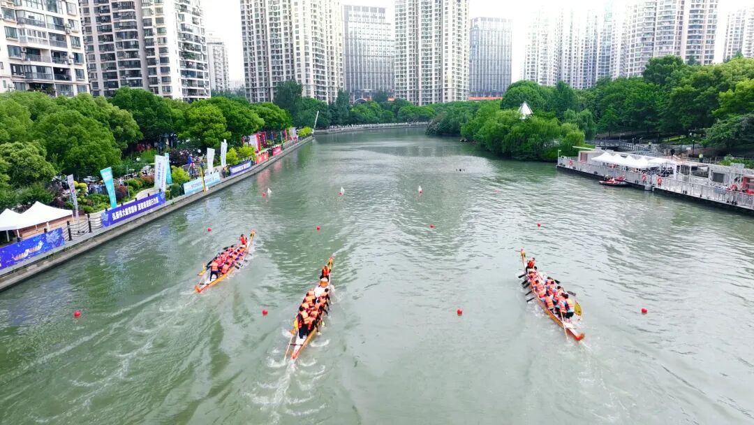 An aerial view shows dragon boats racing along Suzhou Creek against the backdrop of Shanghai