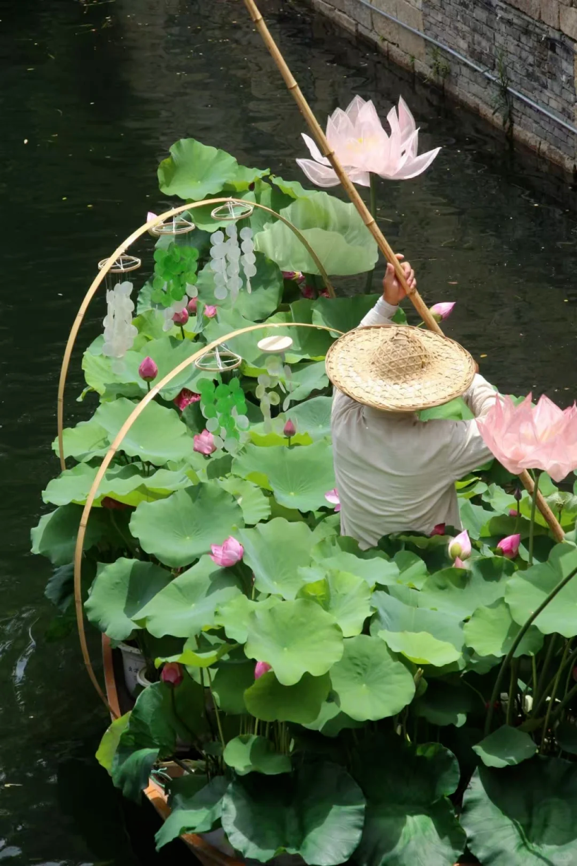 A rowboat carrying a full load of fresh lotuses glides along the river..png