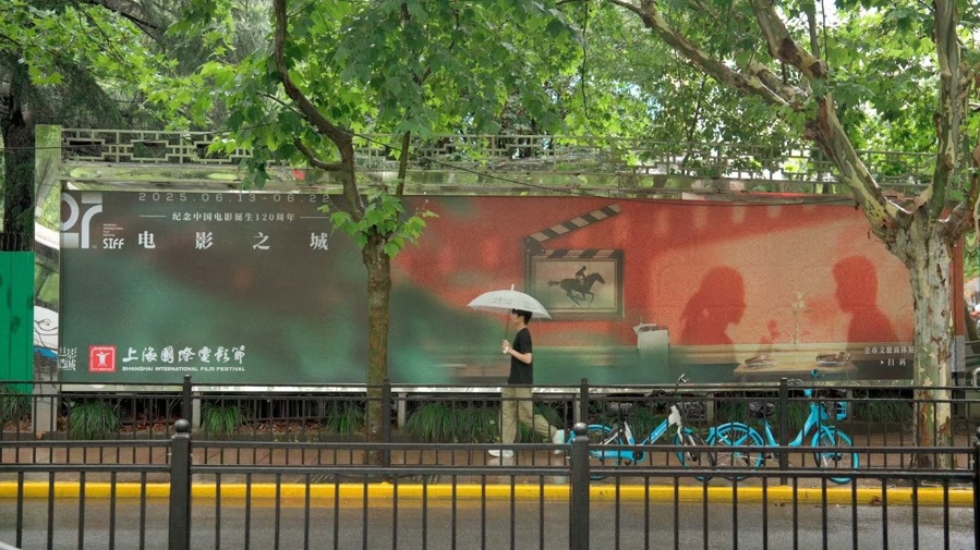 A passenger walks past a poster for the 27th Shanghai International Film Festival in the rain.jpeg