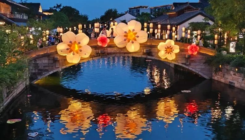 The flower-shaped lights illuminate the water