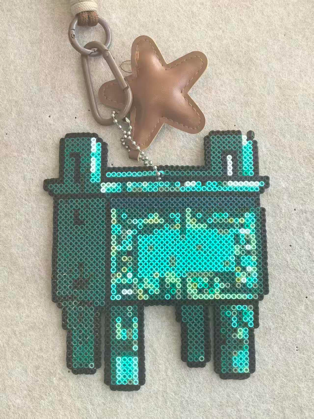 A bronze vessel-shaped keychain made from beads.png
