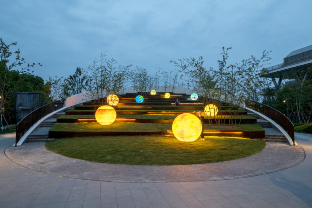 The eight sculptures are illuminated at night.png