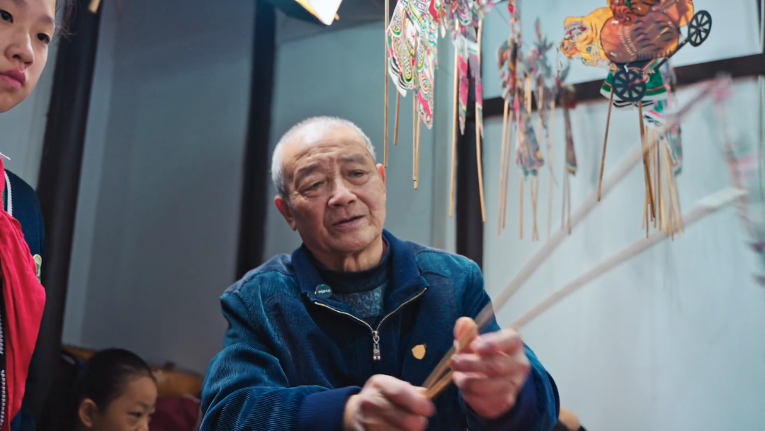 A shadow puppetry master demonstrates the art to children.png