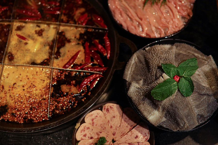 A spicy hotpot surrounded by food.jpg